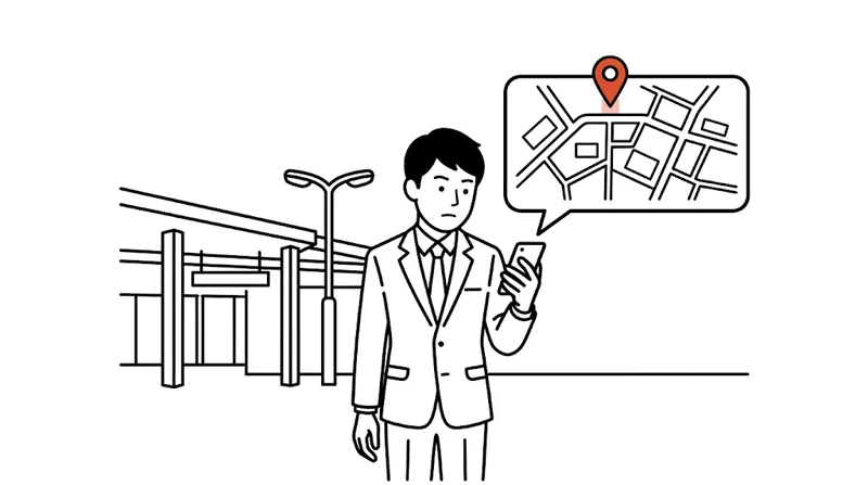 駅前でスマホの地図を見て店を探す会社員。地図のいちばん上にピンが立っている